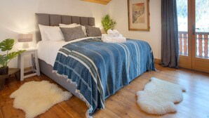 A bedroom with a bed, a nightstand, a lamp, a plant, a framed picture, and a balcony with a view. - 5☆ Chalet, 15 ppl, spa, pet-friendly, La Clusaz (La Clusaz)
