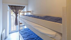 A dormitory room with bunk beds, a window with curtains, and a view of the street outside.