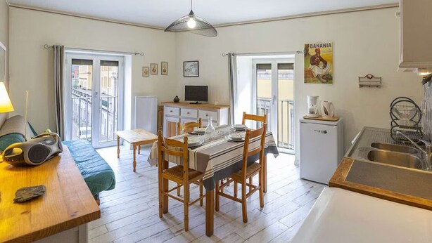 A compact kitchen with a dining area, a small refrigerator, a coffee maker, and a dining table with chairs.