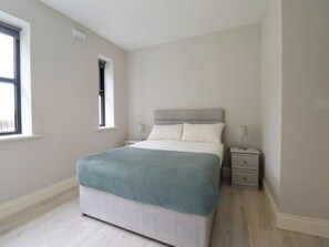 A bedroom with a bed, bedside tables, a window, and a door. - Charming 2-bed Apartment in Dublin's Countryside (Ballyboghil)