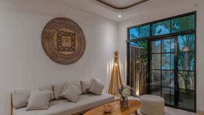 Un salon moderne avec un canapé, une table basse et une grande fenêtre donnant sur un paysage verdoyant.