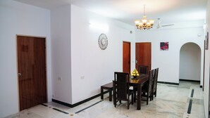 Un comedor con una mesa y sillas de madera, una araña y un reloj en la pared.