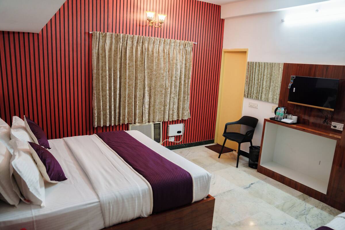 A hotel room with a bed, a desk, a chair, a television, and a curtain.
