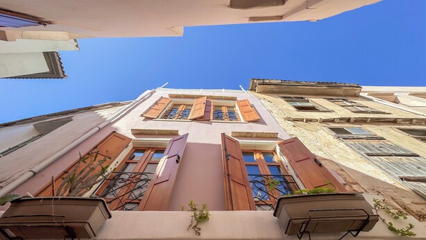 A building with multiple windows, some with shutters, and balconies with metal railings. - Vetus Oppidum Guesthouse (Chania)