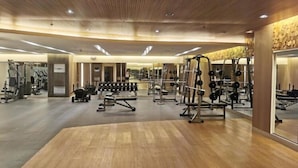 Un'ampia palestra con diverse attrezzature per l'allenamento, pavimento in legno e un moderno design del soffitto.