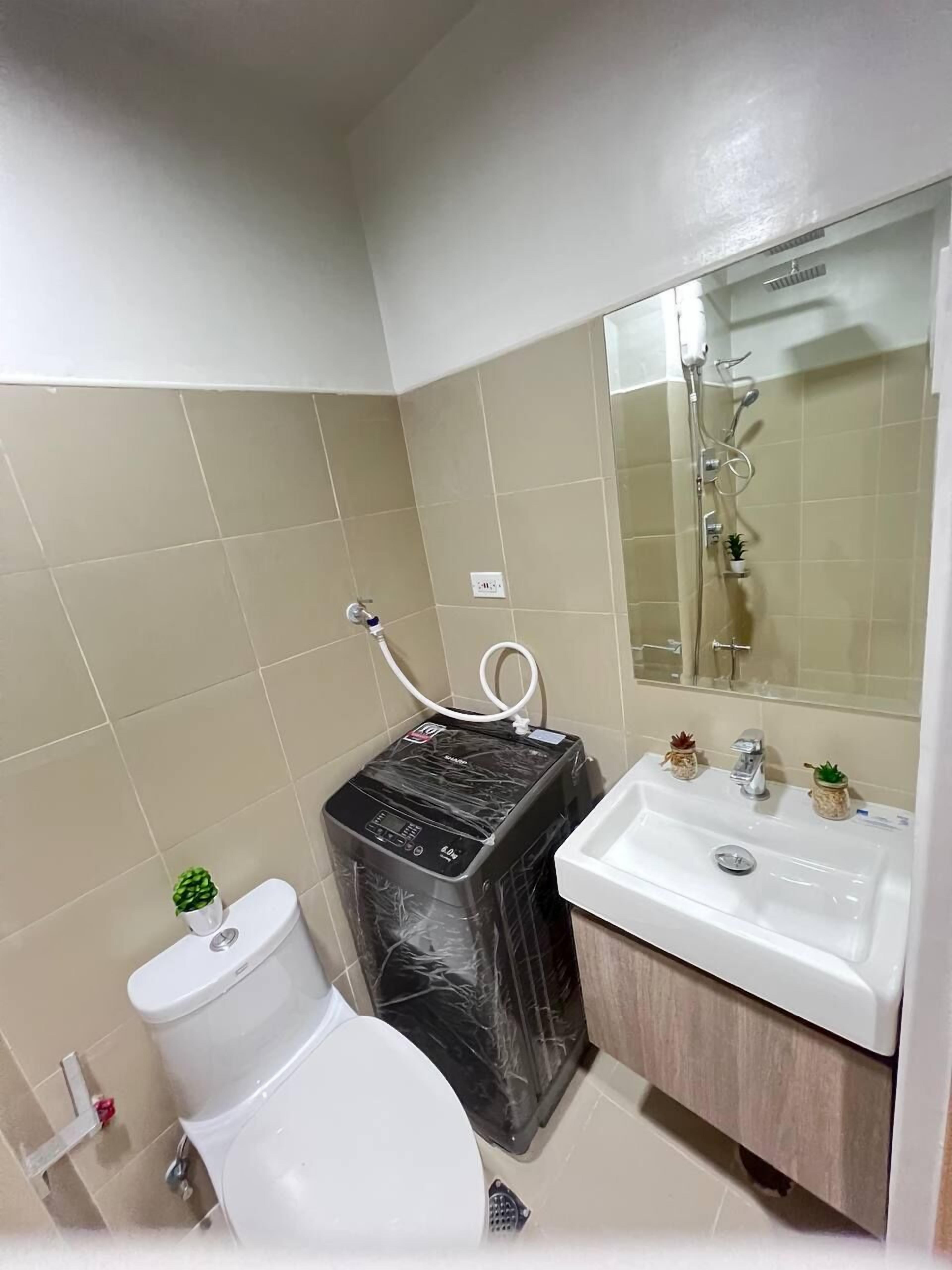 A bathroom with a toilet, a black water heater, a sink, and a mirror.
