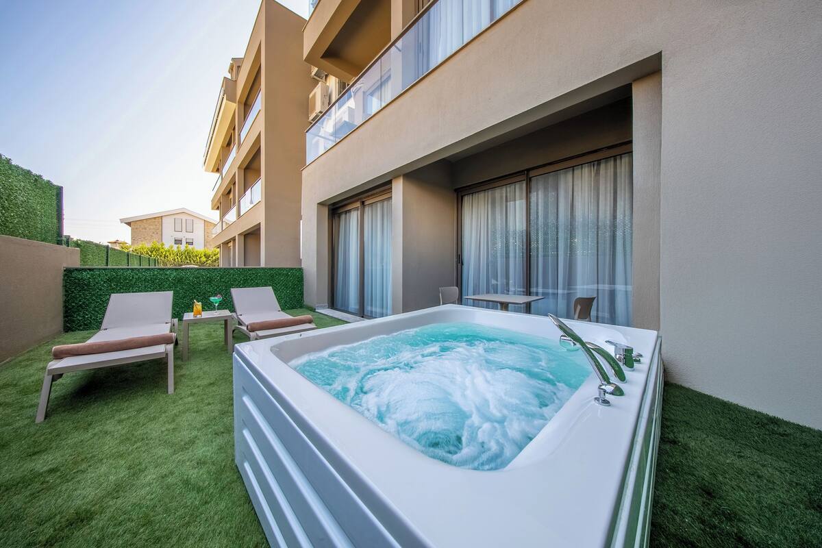 A spa area with a hot tub, two lounge chairs, and a small table with a drink.