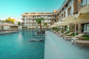 A swimming pool with lounge chairs and umbrellas, surrounded by a building with multiple floors and balconies. - Prive Suite Side & Spa Hotel (Manavgat)
