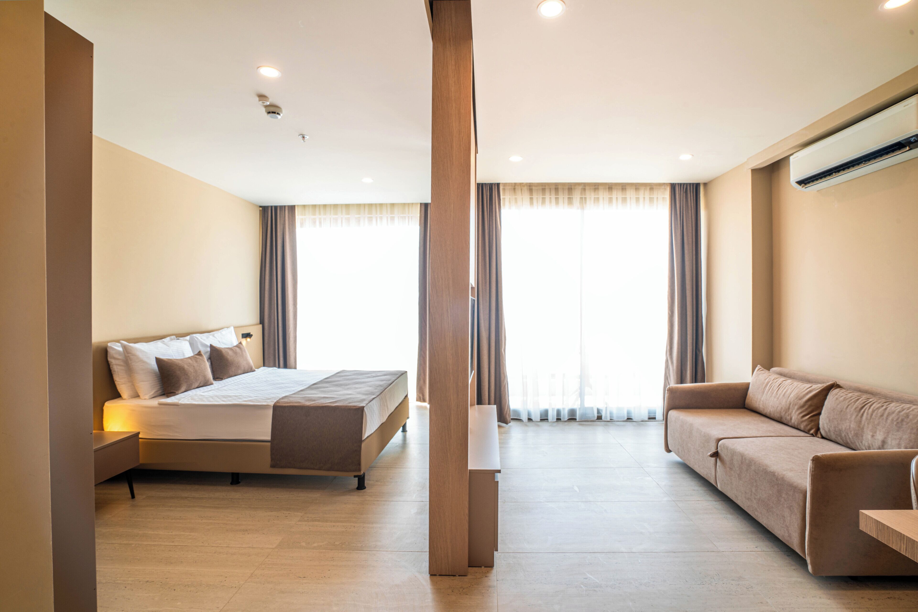 A modern hotel room with a bed, a sofa, and a desk.