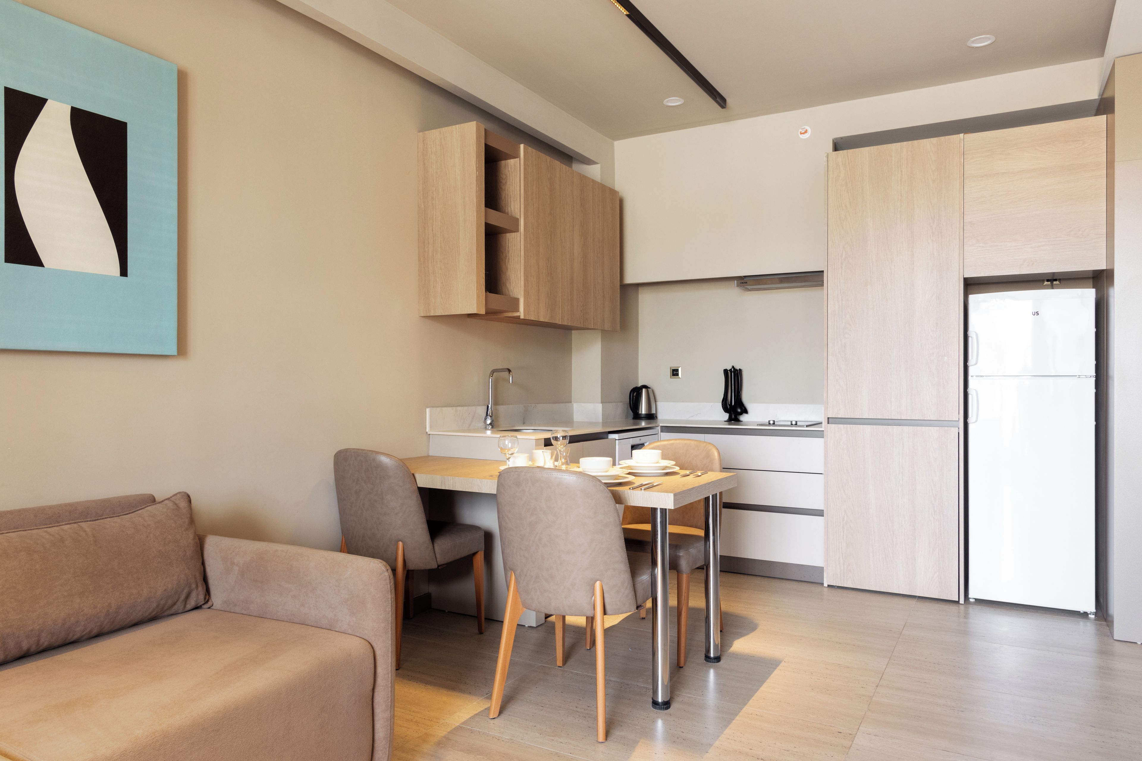 A modern kitchen with a dining area, wooden cabinets, and a sofa.