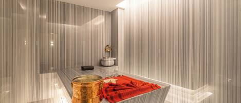 A modern bathroom with a marble vanity, a gold container, and a red towel.