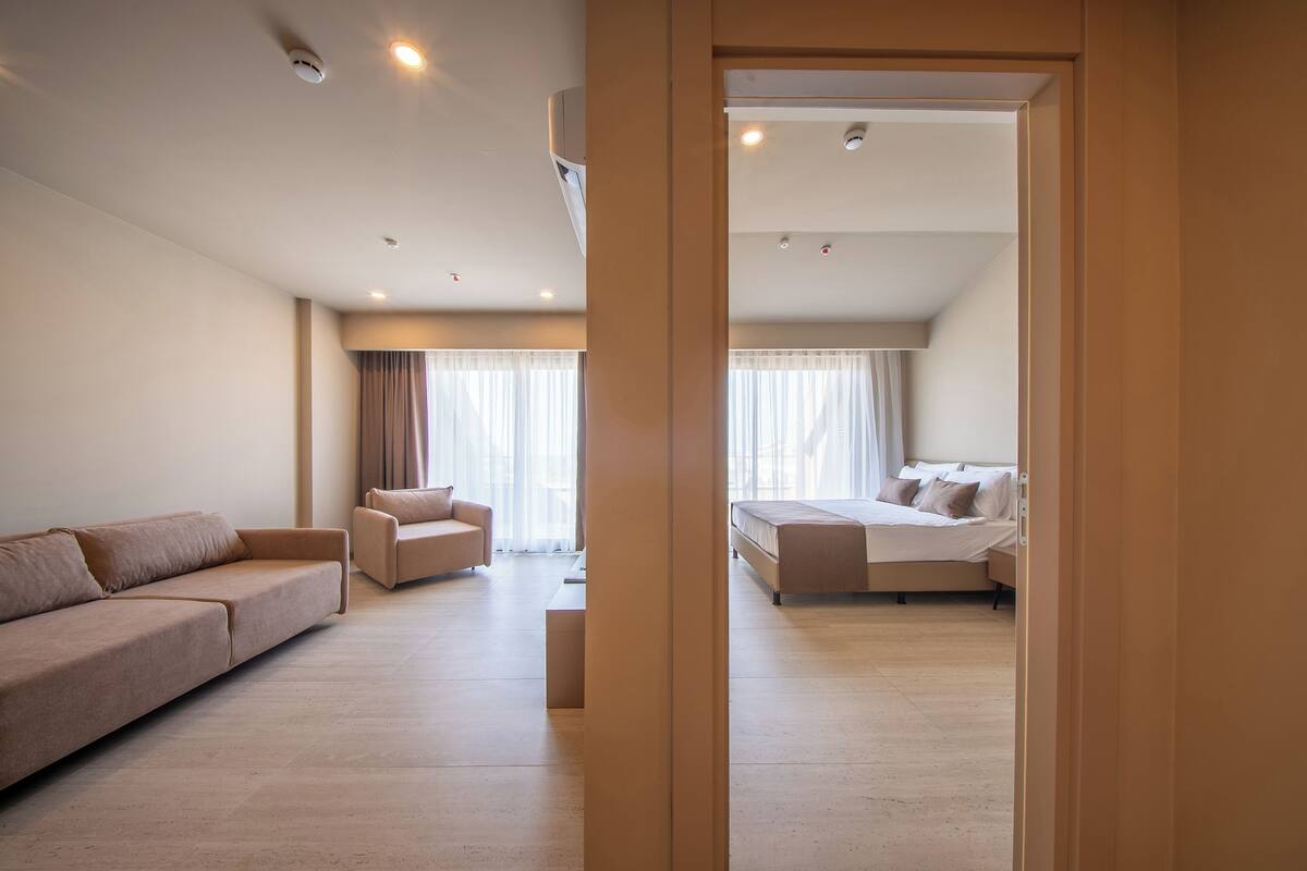 A modern hotel room with a large bed, a sofa, and a chair.