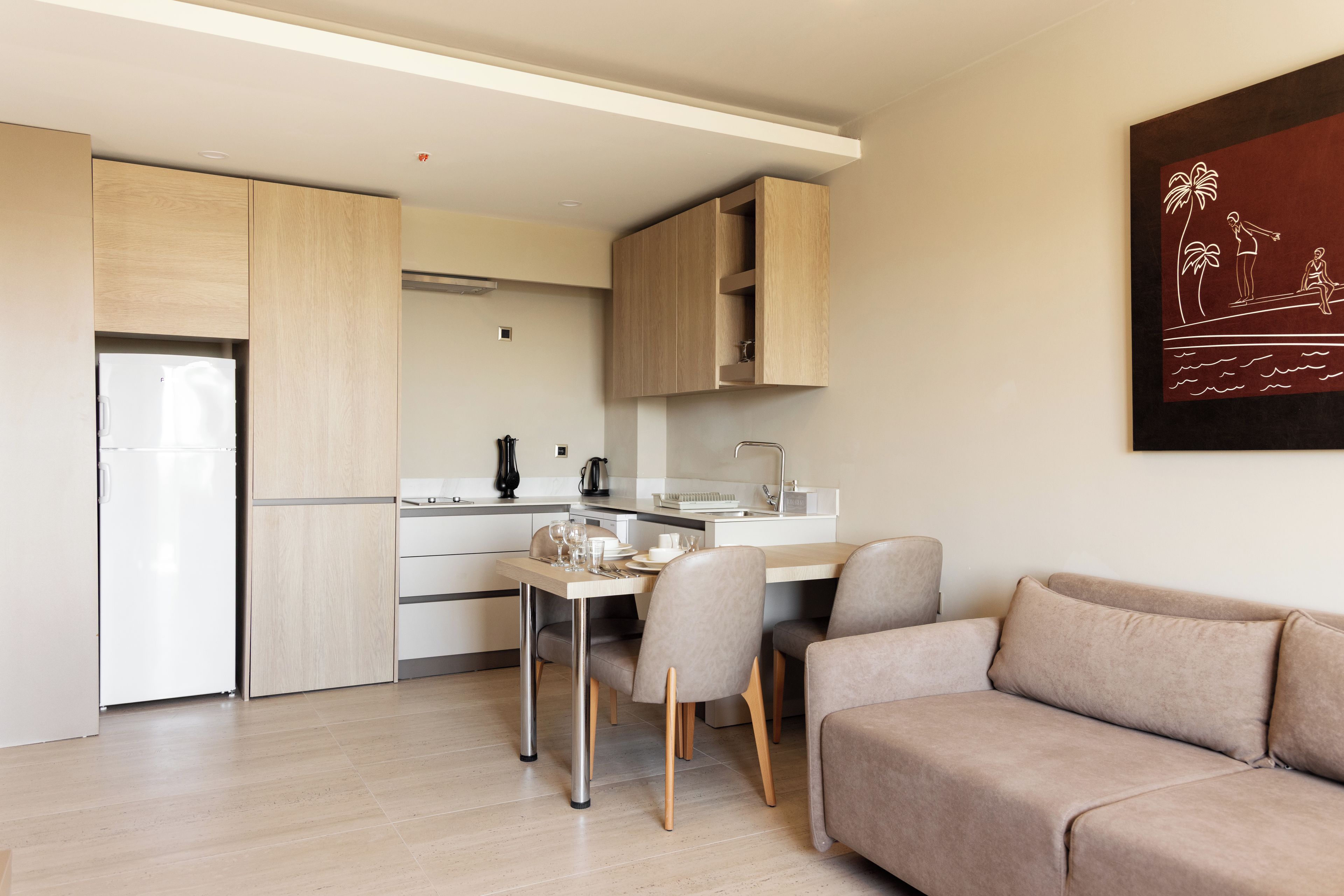 A modern kitchen with a dining area, a sofa, and a wall-mounted artwork.