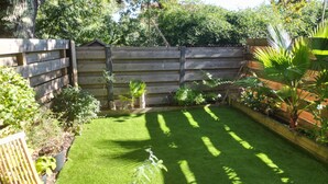 A well-maintained garden with a wooden fence, a variety of plants, and a neatly trimmed lawn.
