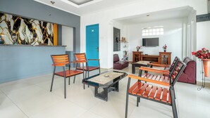 A modern living room with a pool table, orange and black chairs, a blue door, and a TV on the wall. - Rehat at Paskal Pelangi (Bandung)