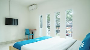 A hotel room with a bed, a desk, a chair, and a TV mounted on the wall. - Rehat at Paskal Pelangi (Bandung)