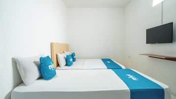 Una habitación de hotel con cama, almohadas, televisor y repisa.