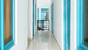 A hallway with blue doors and white walls, leading to a staircase with a black railing. - Rehat at Paskal Pelangi (Bandung)