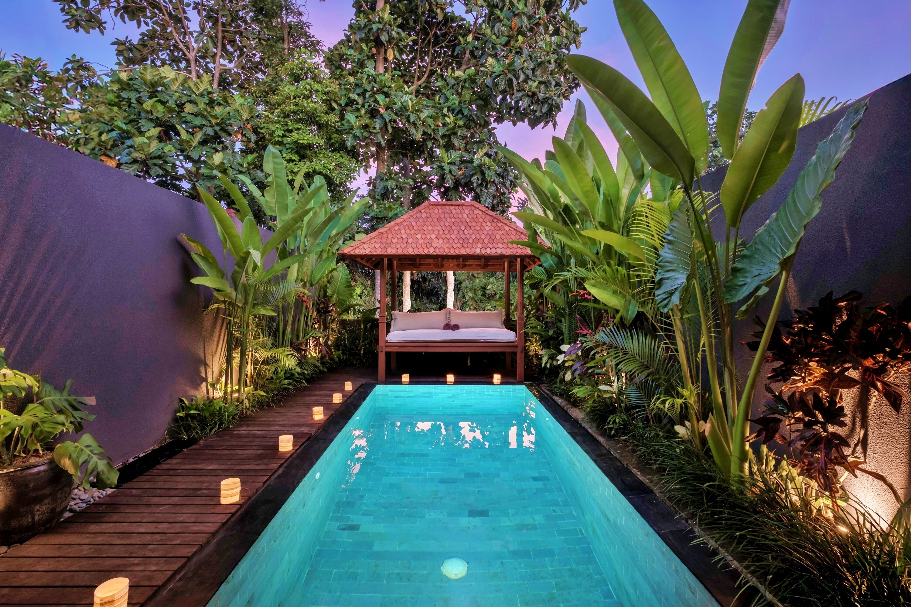 Una piscina rectangular con un muelle de madera que conduce a un gazebo con techo rojo.