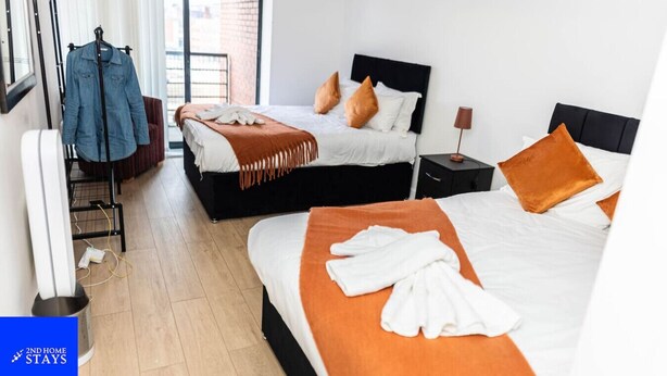 Une chambre d’hôtel avec deux lits, une armoire, un bureau et une fenêtre avec des stores.