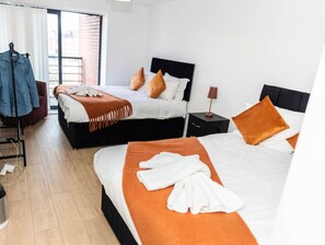 A hotel room with two beds, a wardrobe, a desk, and a window with blinds. - 2ndHomeStays I Birmingham | Ensuite | Parking&WiFi (West Midlands)