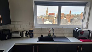 Eine Küche mit Blick auf Gebäude, einem Spülbecken, einem Toaster, einem Wasserkocher und einer Kaffeetasse.