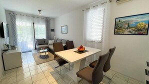 A modern living room with a sofa, a dining table with chairs, a coffee table, and a TV. - Apartment Zlata (Jadranovo)