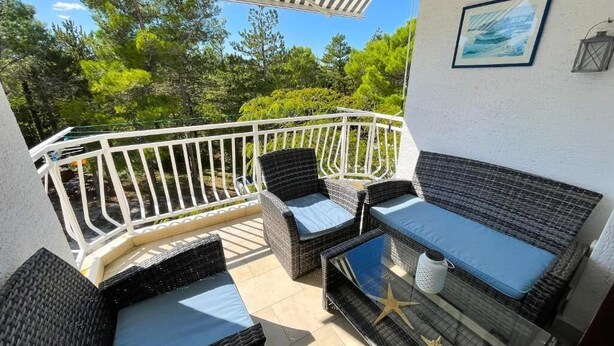 A balcony with wicker furniture, a glass table, and a starfish decoration. - Apartment Zlata (Jadranovo)