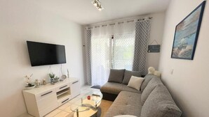 A modern living room with a flat-screen TV, a sofa, a coffee table, and a white cabinet. - Apartment Zlata (Jadranovo)