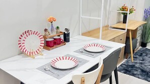 A dining area with a white table, two chairs, and a white metal shelf unit with a mirror. - Unistay Shore3 Poolview w bal (Pasay)