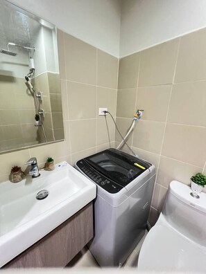 Une salle de bain équipée d’un lavabo, d’un miroir, d’une douche et de toilettes.