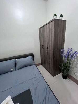 Une chambre à coucher avec un lit, une armoire et une plante en pot.