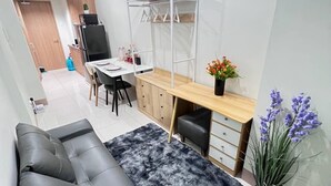 A compact living space with a sofa, a dining table, a bunk bed, and a small kitchen area. - Unistay Shore3 Poolview w bal (Pasay)