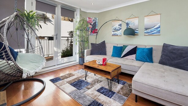 A living room with a sofa, a hanging chair, a coffee table, and a large window. - Stylish Balcony Apartment by London Fields - Pass the Keys (London)