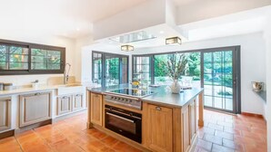 A spacious kitchen with a large island, ample natural light, and a view of greenery outside.