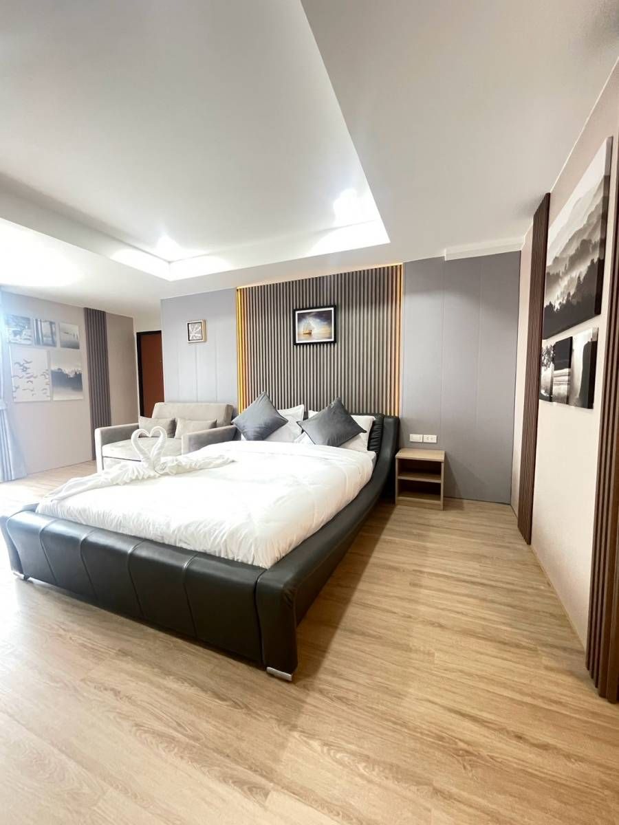 A modern bedroom with a large bed, a bedside table, and a wall-mounted TV.
