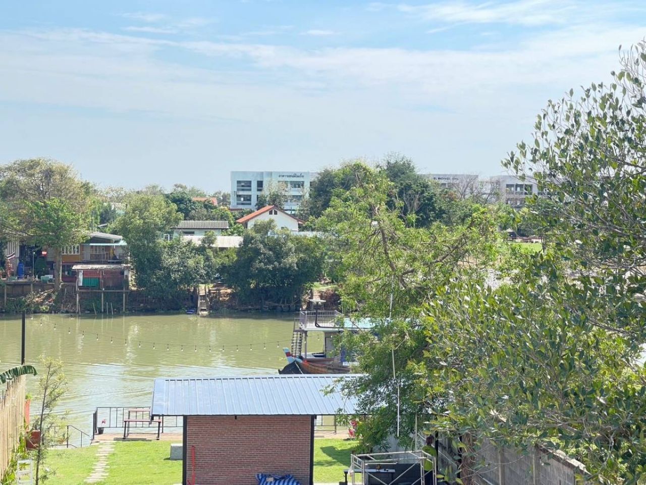 A riverside view with a small dock, a brick building, and a white building in the background.