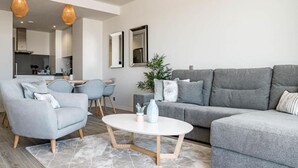 Una sala moderna con un sofá gris, un sillón a juego, una mesita de centro y un comedor con sillas y una mesa.