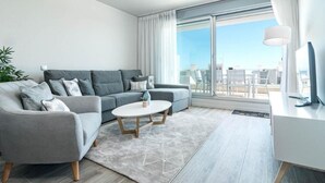 Una sala de estar moderna con un sofá gris, una mesa de centro redonda y un escritorio blanco.