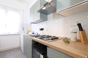 A modern kitchen with a gas stove, a coffee maker, and a knife block.