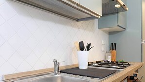A modern kitchen with a stainless steel sink, a gas stove, and a white utensil holder.