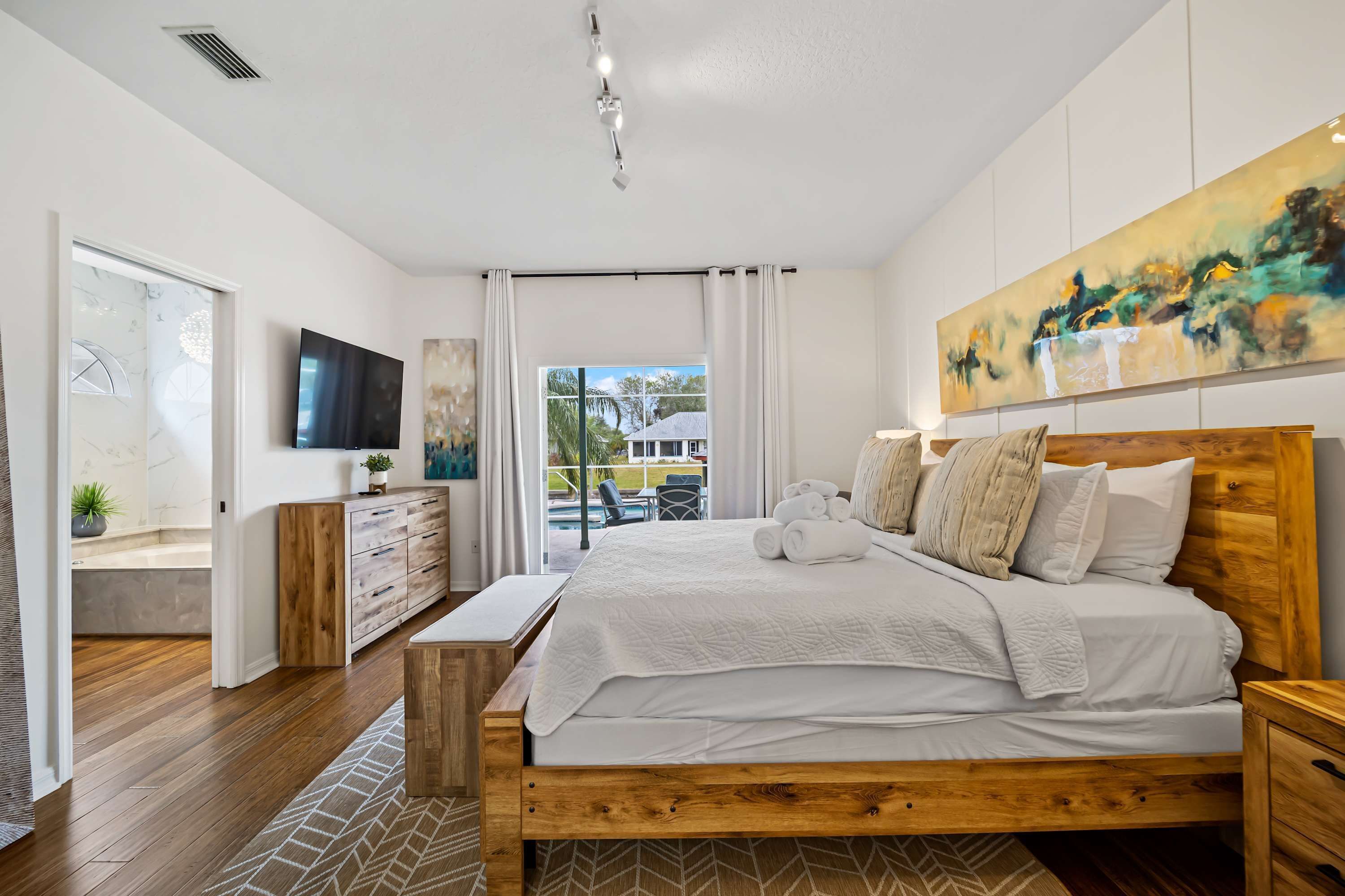 Un dormitorio moderno con una cama de madera, un televisor de pantalla plana, un cuadro y vistas al exterior.