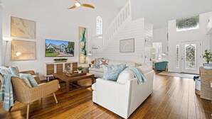 A spacious living room with a white sofa, wicker chair, and wooden flooring. - Bring Your Boat Heated Pool spa Dock Beach (Palm Coast)