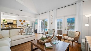 A modern living room with a wooden coffee table, white sofas, and wicker chairs. - Bring Your Boat Heated Pool spa Dock Beach (Palm Coast)
