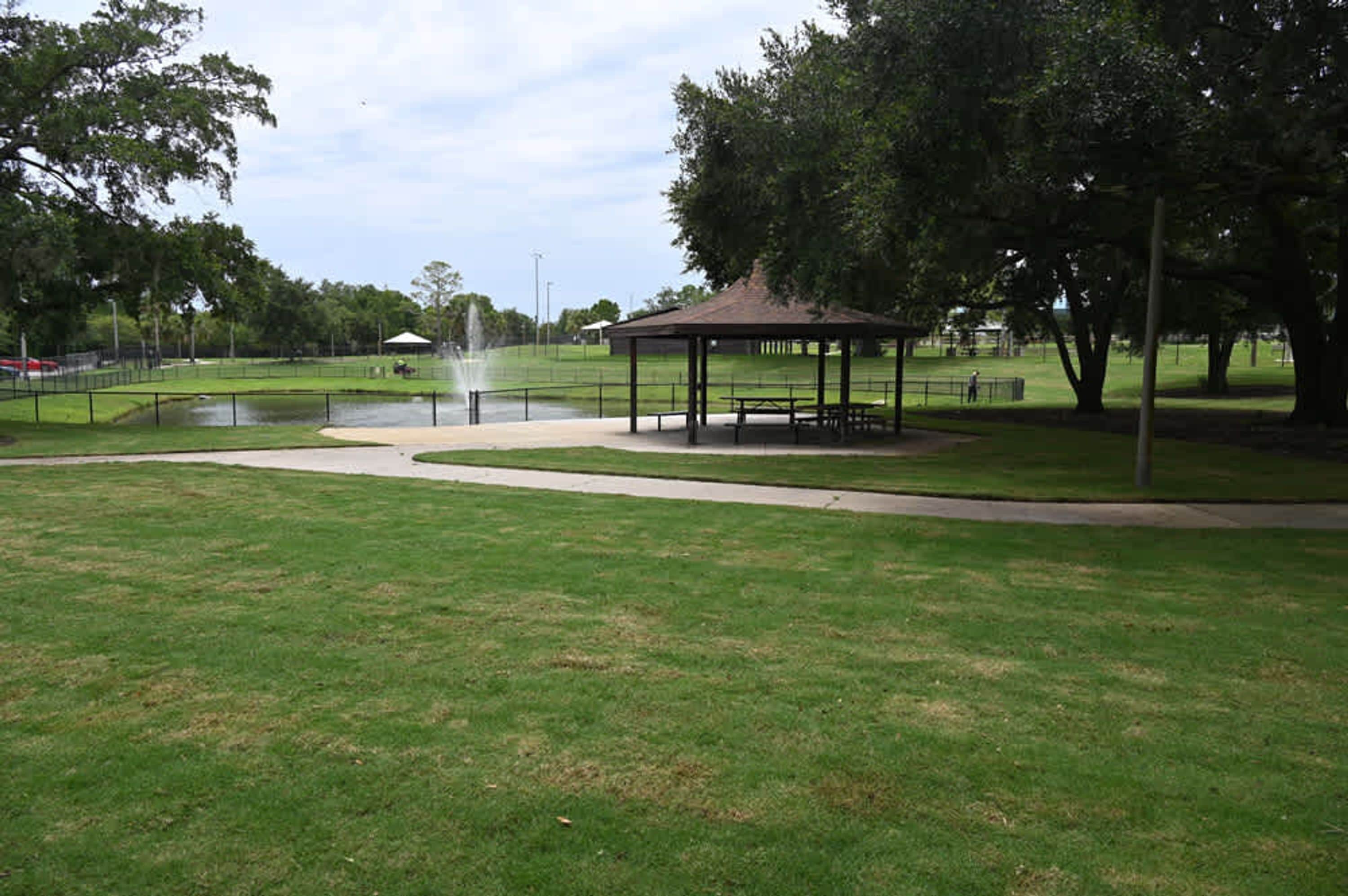 Un parque con un pabellón, una fuente y un estanque.