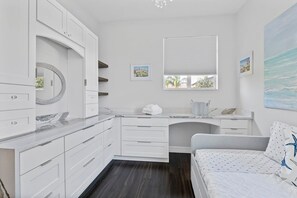 Une salle de bain moderne avec un meuble-lavabo blanc, un grand miroir et une fenêtre équipée de stores.