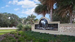 A sign for Palm Coast with palm trees and greenery around. - Perfect Paradise Vacation in Tranquility - Salt Water Pool (Palm Coast)