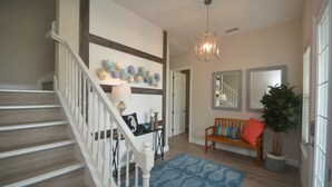 A staircase with a white railing, a blue patterned rug, a wooden bench with cushions, and a potted plant. - Beach Front 5 bed 4 Bath Luxury House Hot Tub Fenced Yard Pets Welcome (Palm Coast)