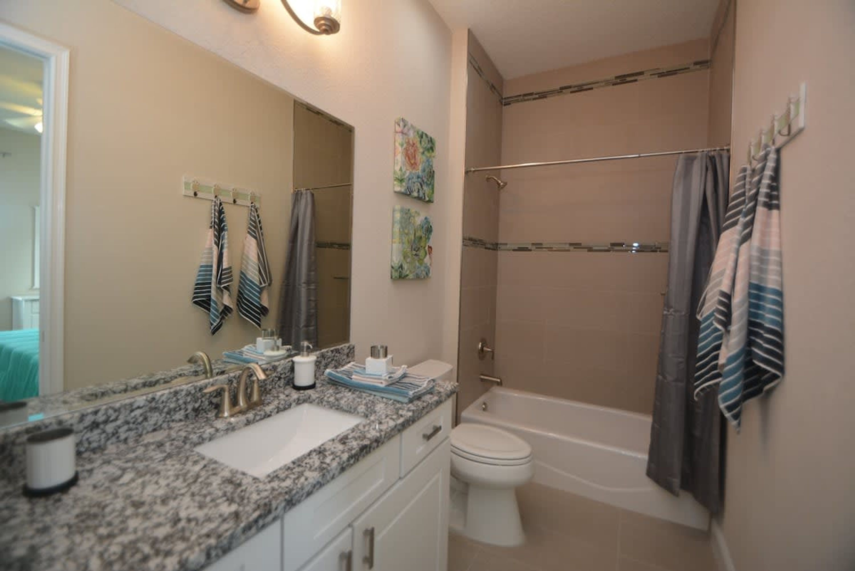 A bathroom with a granite countertop sink, a white toilet, and a walk-in shower.