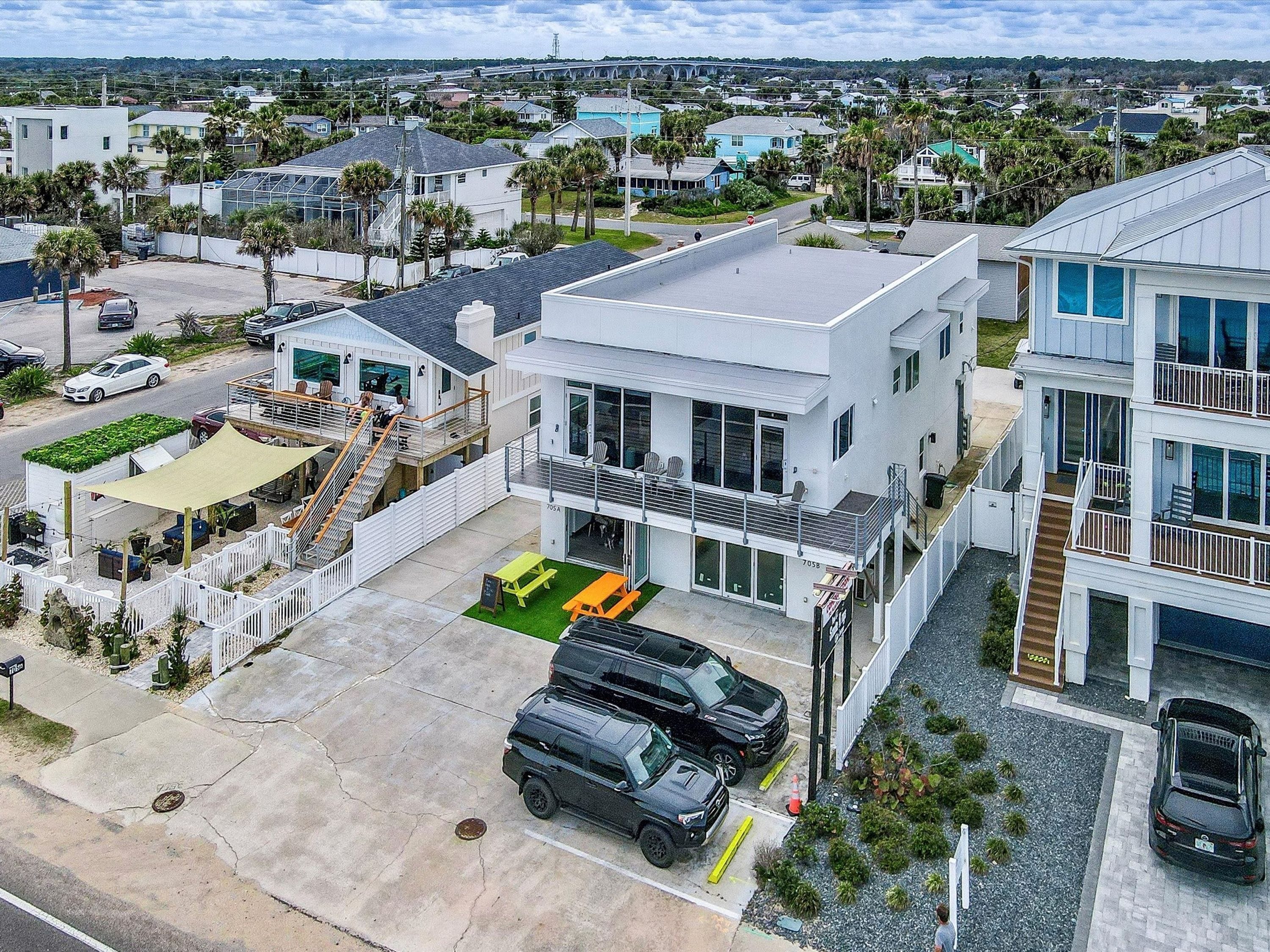 A modern multi-story residential building with a spacious driveway, a covered outdoor seating area, and a visible garage.